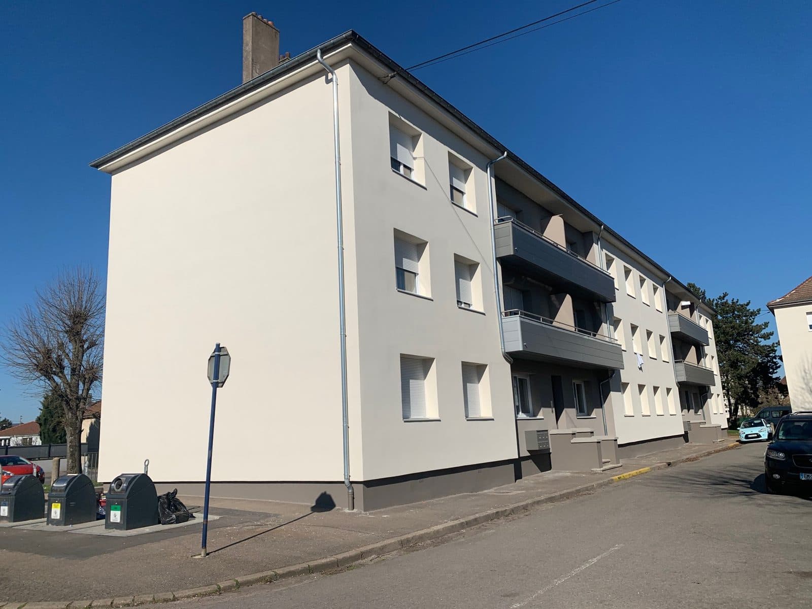 Immeuble de trois niveaux isolé par l'extérieur, enduit clair et soubassement taupe.